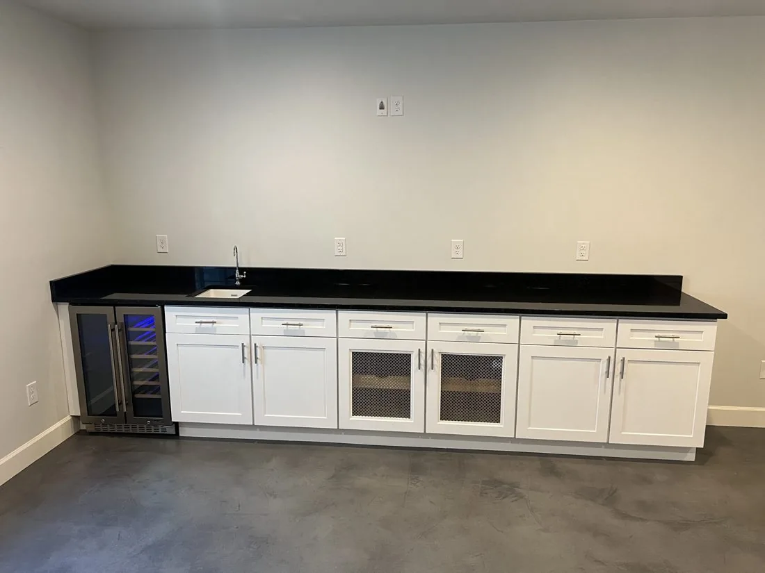 Basement bar with white cabinets and black countertop