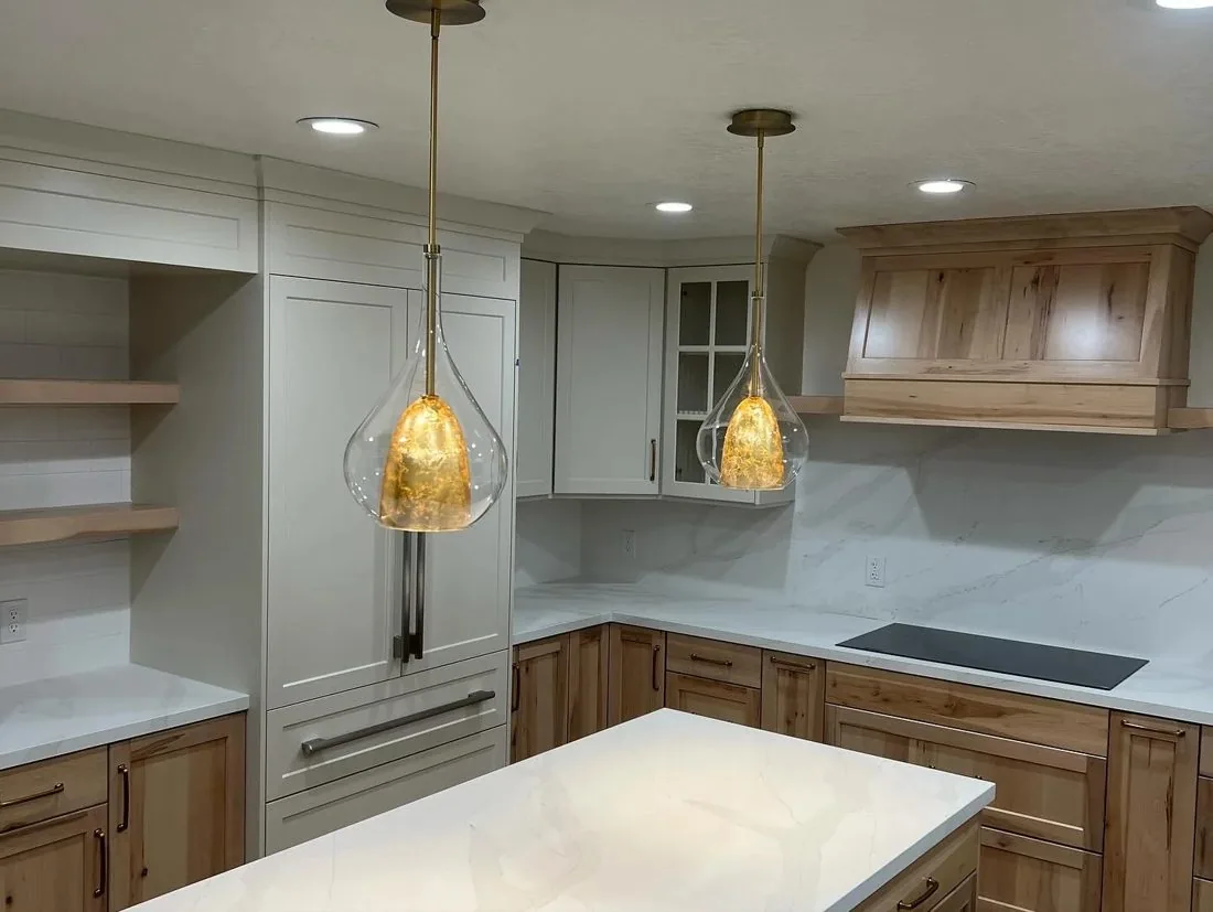 Hickory cabinet detail with gold pendant lights and glass uppers