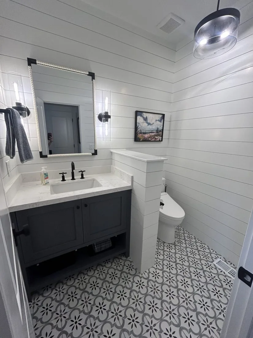 Bathroom remodel with navy vanity, shiplap wall, and patterned tile floor