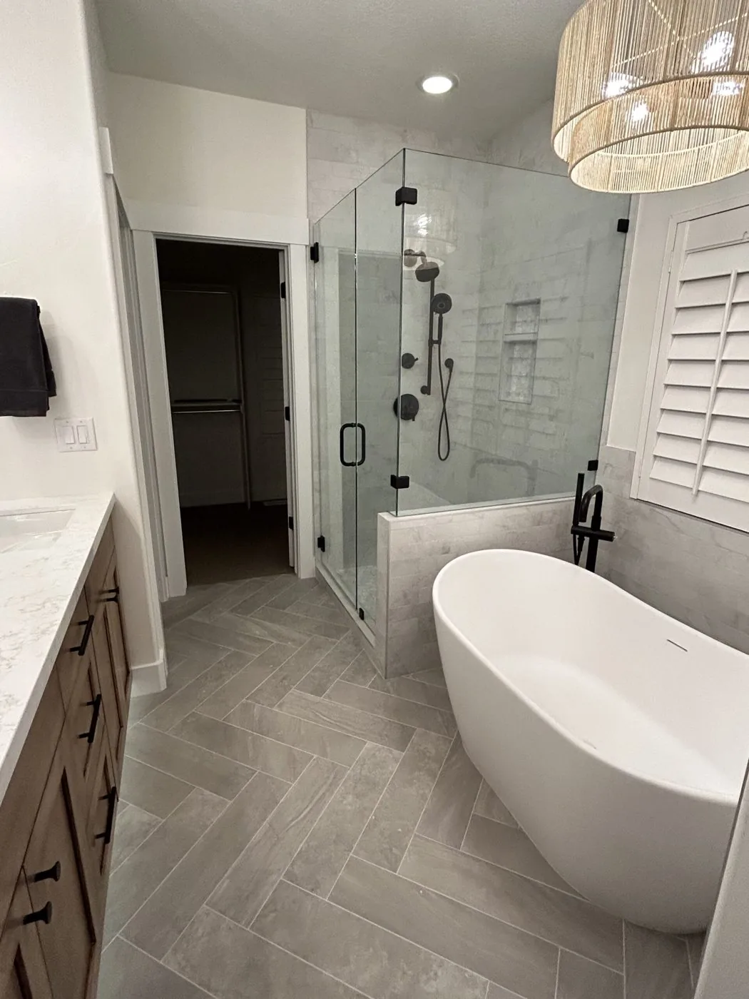 Remodeled bathroom with freestanding tub, glass shower, and herringbone tile floor