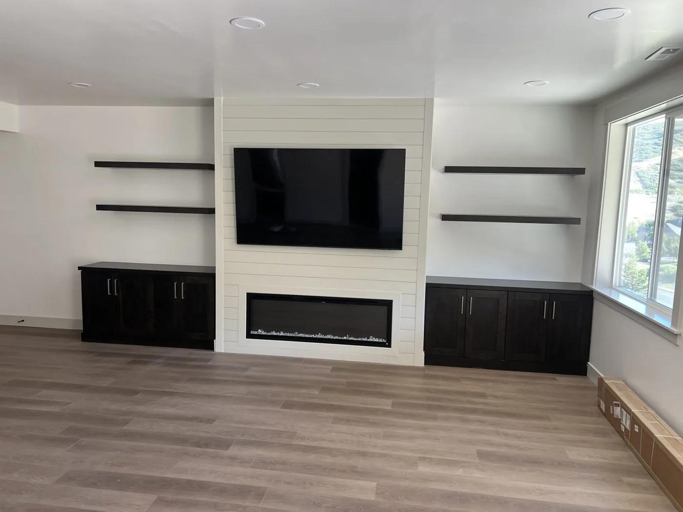 Custom shiplap media wall with dark built-in cabinetry and floating shelves